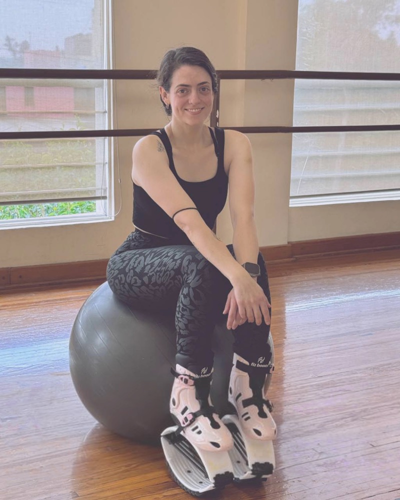 Michelle sentada en un balón en el estudio, con sus botas de rebote puestas